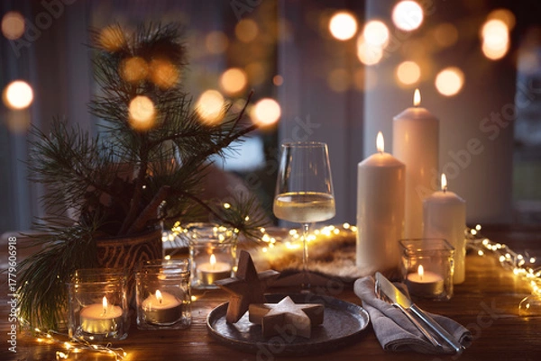 Fototapeta Elegant table decoration for a christmas dinner. Romantic dinner concept with burning candles in the evening at a restaurant. Close-up with golden bokeh lights. Background for seasonal an holiday gast