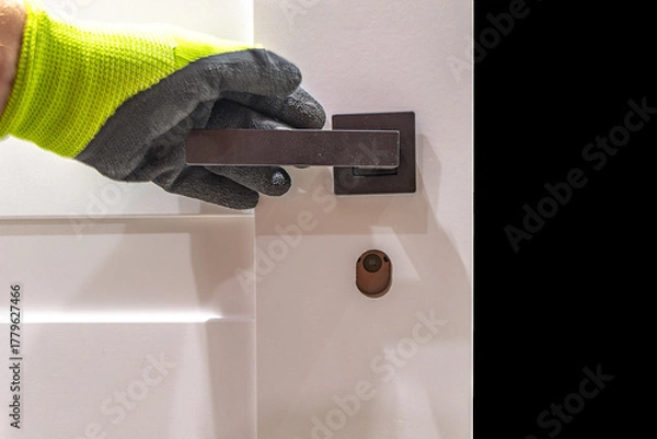 Fototapeta Installation of a black door handle with a lock for a white wooden door,