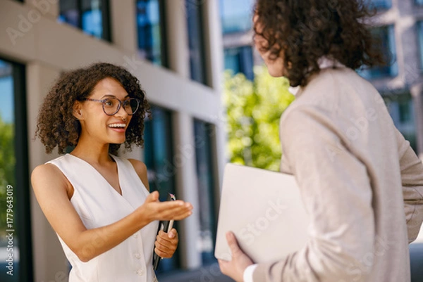 Fototapeta woman and man exchange greetings and contact information outside work area during networking event