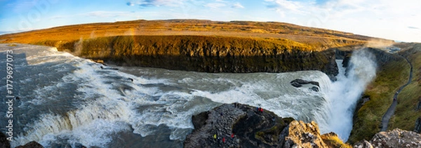 Obraz Gullfoss waterfall in Iceland showcases powerful cascades flowing into a canyon. Visitors admire the natural beauty from nearby viewpoints, especially during sunny weather.