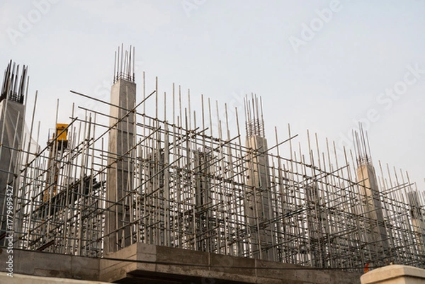 Fototapeta Concrete building under construction with scaffolding and steel bars
