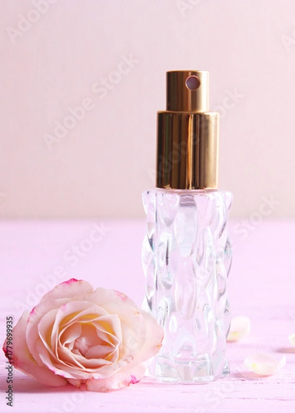 Fototapeta Perfume bottle and rose flowers on a light background close up. Vertical photo format