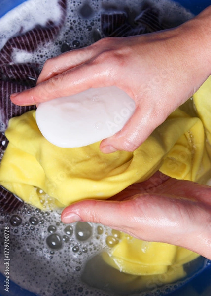 Fototapeta A woman washes clothes with her hands in soapy water. Hand wash clothes. . Vertical photo format