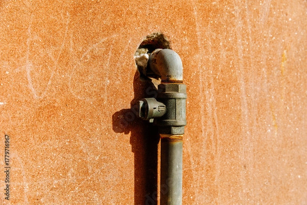 Obraz Rusty metal wall with industrial pipe fixture in bright sunlight