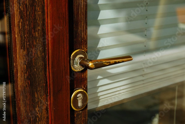 Fototapeta Wooden door handle with brass lock and blinds in sunlight