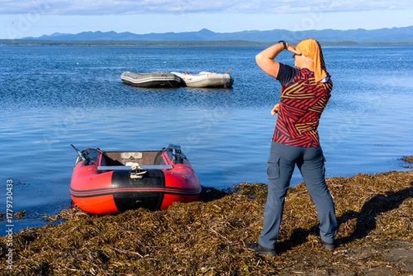 Fototapeta Person enjoying a sunny day by the water while gazing at distant boats in the calm sea