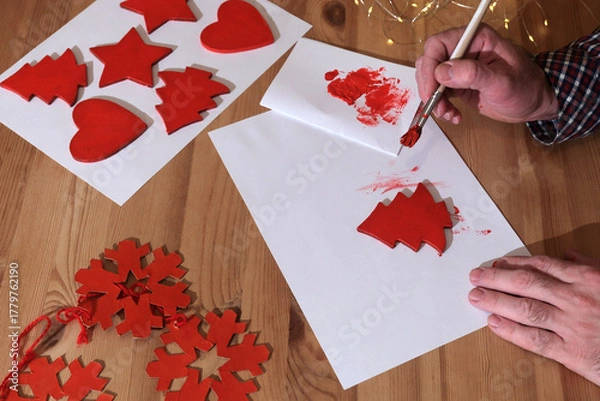 Obraz Person painting red christmas tree or winter holiday. preparing for the new year