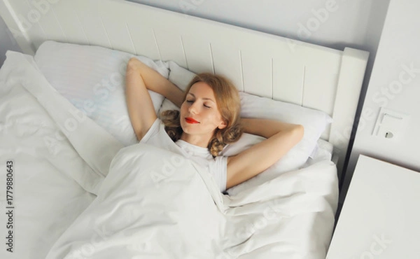Fototapeta Woman sleeping lying in bed on white soft comfortable pillow in bedroom at home
