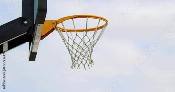 Fototapeta Showing basketball hoop with orange rim and white net at outdoor court left, copy space