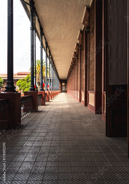 Fototapeta Long perspective view of a historical architectural corridor with columnsSymmetrical corridor with repeating columns and warm natural light, showcasing historic architecture,.