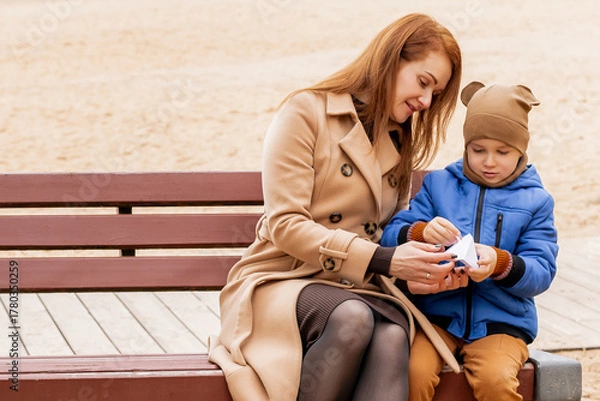 Fototapeta Happy Mother and Son Holding a Handmade Paper Boat Together in Autumn Park