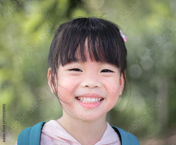 Fototapeta Portrait of a cute little asian girl smiling in the park