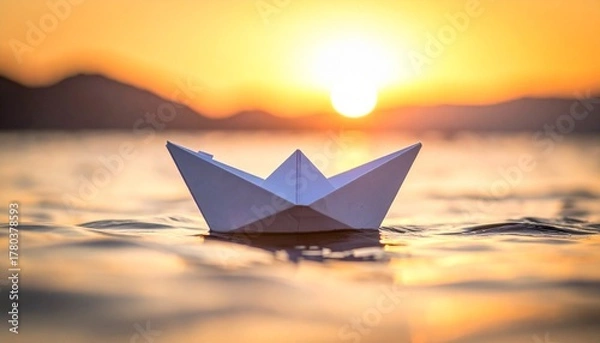 Obraz A white paper boat floats on golden water at sunset, cradling a crumpled note—evoking simplicity, reflection, and the poetic rhythm of quiet imagination.