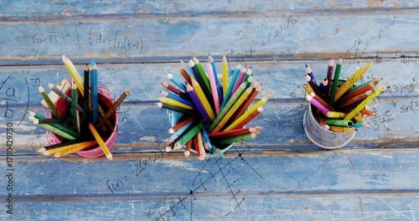 Obraz Showing blue cup brimming sharp colored pencils on worn blue table, with math overlay