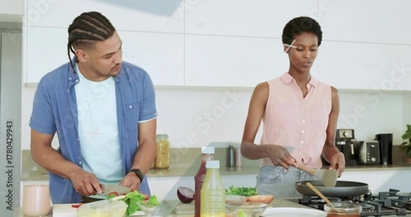 Fototapeta Slicing vegetables while stirring food couple in modern kitchen, with cutting board and frying pan