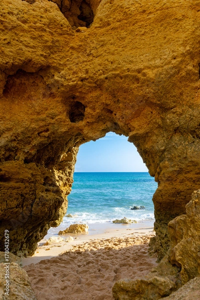Obraz A naturally formed sandstone arch dominates the frame, perfectly framing the azure Mediterranean Sea in a striking contrast of golden rock and blue water