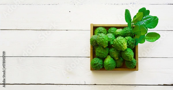 Obraz stack of fresh green bergamot with young leaves in wood box on white table and old brown wood background