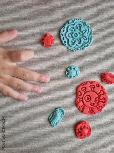 Fototapeta Covid and other respiratory virus molecules made of plasticine. Little toddler education moment in a playful mode. Bacteria made of playdough and kids' hands over the table. 