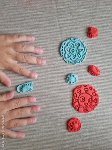 Fototapeta Covid and other respiratory virus molecules made of plasticine. Little toddler education moment in a playful mode. Bacteria made of playdough and kids' hands over the table. 