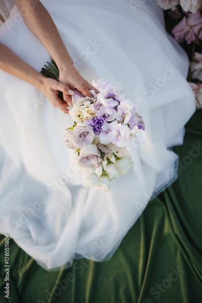 Fototapeta Bridal bouquet held by a bride in a flowing gown