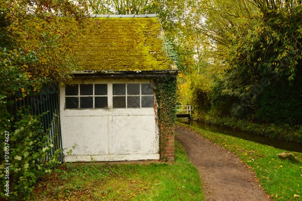 Fototapeta Old Mossy Canal Cottage Beside Bridge in English Countryside