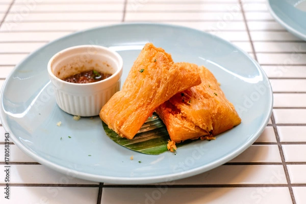 Obraz Golden fried cassava served on a light blue plate with white background. Perfect for restaurant menu design, tropical food promotion, or culinary asia traditional snacks.