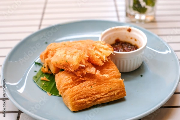 Obraz Golden fried cassava served on a light blue plate with white background. Perfect for restaurant menu design, tropical food promotion, or culinary asia traditional snacks.
