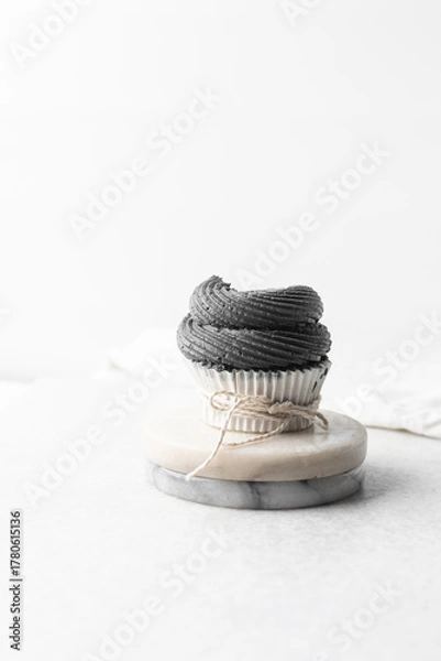 Fototapeta grey frosting on cupcakes with a white background, cupcakes in white liners with tall buttercream swirl, grey buttercream frosted cupcakes on a white background