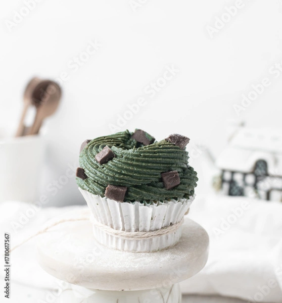 Fototapeta green frosting on cupcakes with a white background, cupcakes in white liners with tall buttercream swirl, green buttercream frosted cupcakes on a white background