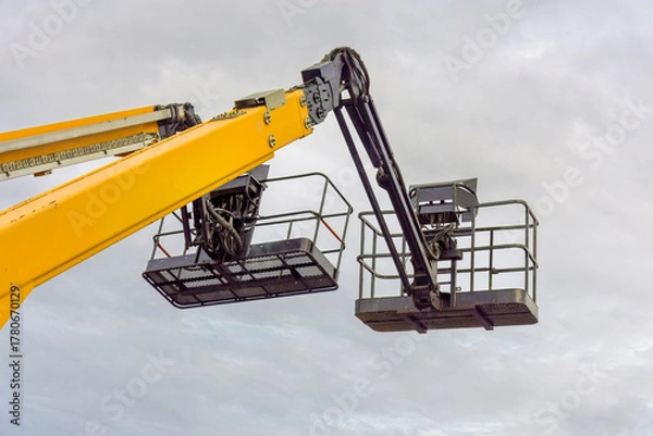 Obraz aerial platforms with work baskets stand out against a dark gray sky