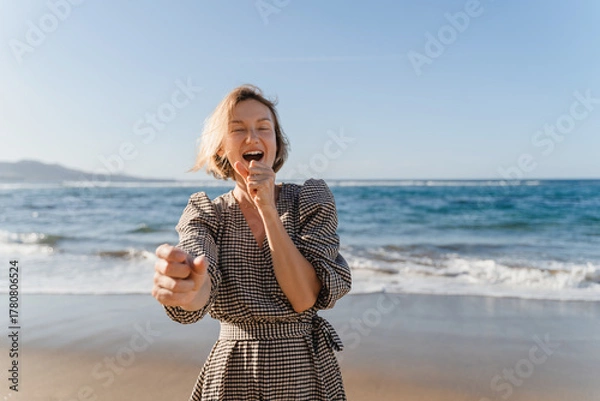 Fototapeta Portrait of happy young woman enjoying fresh air on the beach. Beautiful smiling female having fun on the ocean. Concept freedom and carefree vacation. Beach Holidays.