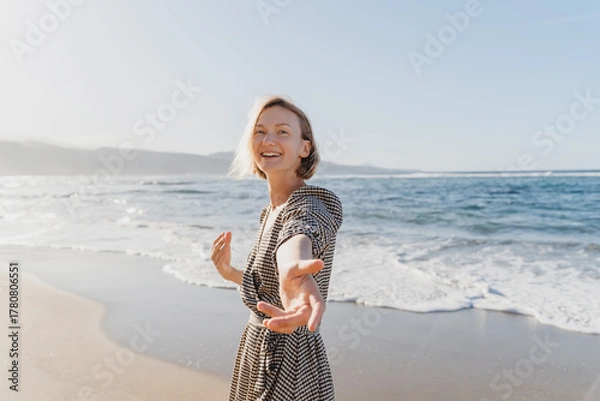 Fototapeta Portrait of happy young woman enjoying fresh air on the beach. Beautiful smiling female having fun on the ocean. Concept freedom and carefree vacation. Beach Holidays.