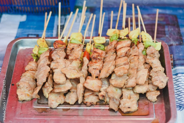 Fototapeta Grilled pork skewers on a tray, some with vegetables.