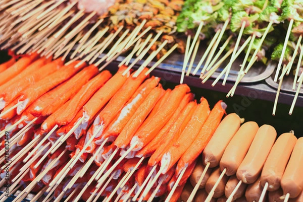 Fototapeta Many bright orange crab sticks on skewers at a food stall.