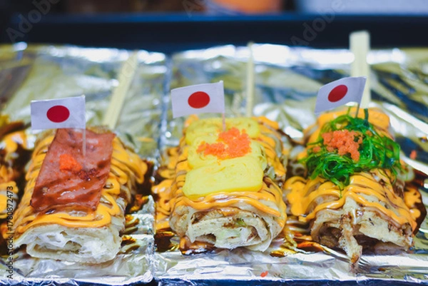 Fototapeta Japanese-style crepes with toppings, sauce, and small flags.