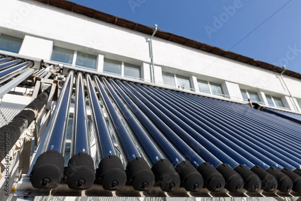 Fototapeta A close-up view of an evacuated tube solar water heater collector. This innovative system, angled towards the sun, represents clean energy, sustainability, and energy-saving technology.