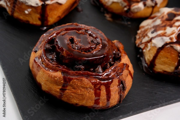 Fototapeta Chocolate roll drizzled with chocolate sauce on slate