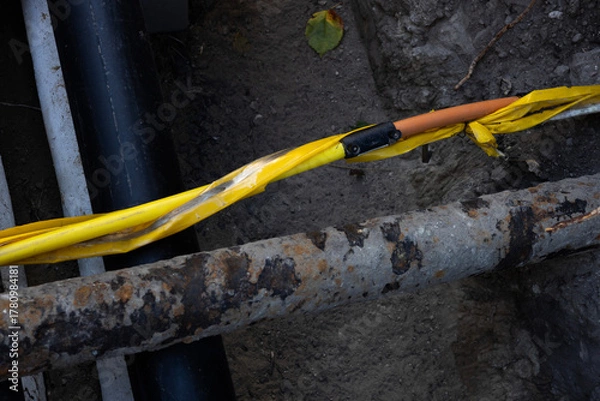 Fototapeta Construction site showing yellow safety tape around exposed utility lines and pipes during maintenance work