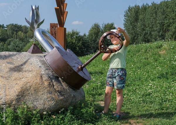 Obraz A little boy is playing in the park and locking a large metal padlock