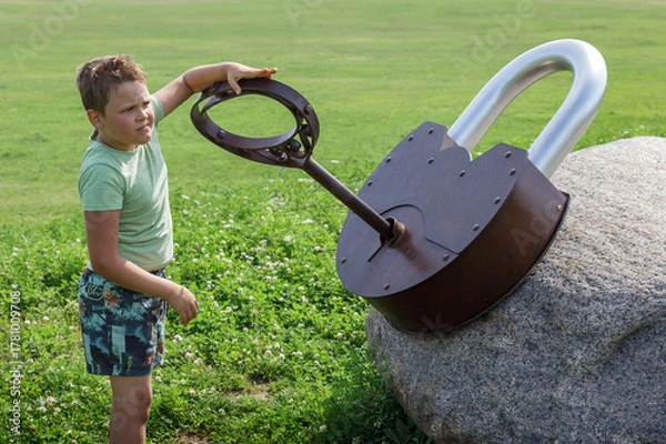 Obraz A little boy playing in the park and trying to unlock a huge lock