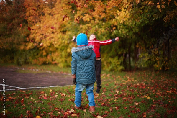 Fototapeta children playing with leaves in autumn park