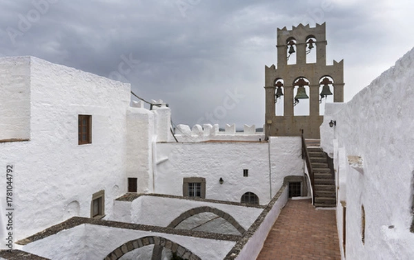 Obraz Whitewashed monastery with bell tower featuring five arched openings and bells surrounded by arched roofs  in a courtyard, in the Monastery of Saint John the Theologian of Patmos, Greece.