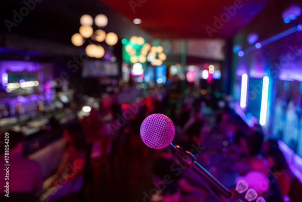 Fototapeta Close up of microphone in bar with blurred crowd in background.