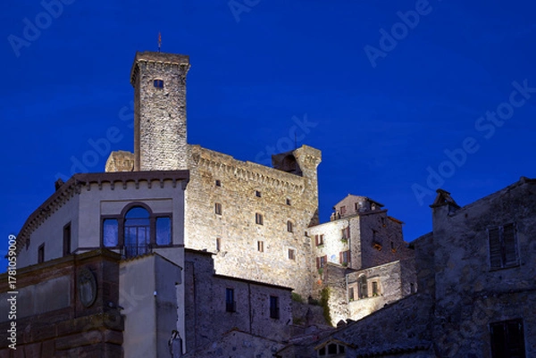 Fototapeta Stone walls of a medieval castle with a tower at night in Bolsena