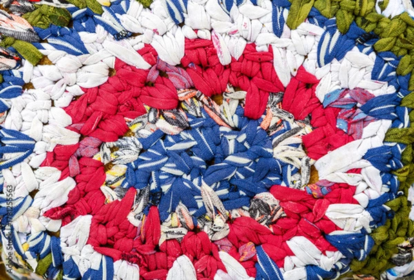 Fototapeta Vintage homespun doormat made from strips of cloth as background. Texture of a homemade rug from different fabrics. Round knit mat