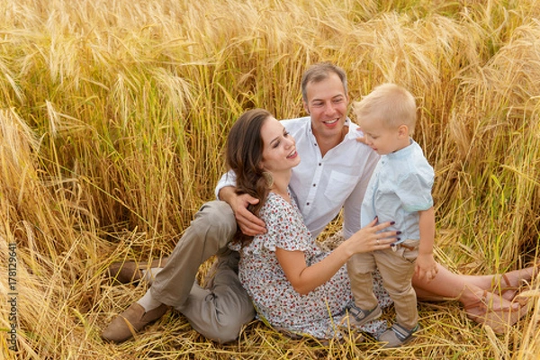 Obraz Family sitting on the grass in a wheat field