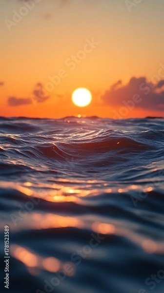 Fototapeta Vibrant orange sunset over the ocean with gentle waves reflecting the warm light creating a serene and beautiful seascape at dusk