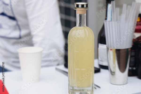 Fototapeta Barman mixing liquor beverages and alcohol drinks in plastic cups, bartender working, beautiful row line of different coloured cocktails on open air summer party in a bar, catering on banquet event
