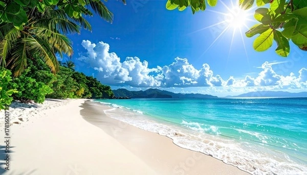 Fototapeta Turquoise Ocean Waves Gently Lap White Sand Beach Under Bright Blue Sky with Sunburst and Lush Green Foliage in Foreground