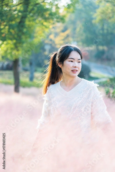 Fototapeta Young woman standing in pink flowering plants outdoors
